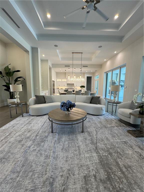569 Neapolitan Way Naples, FL 34103 - Photo 2 of 50 Living area with a tray ceiling, recessed lighting, ceiling fan with notable chandelier, and visible vents