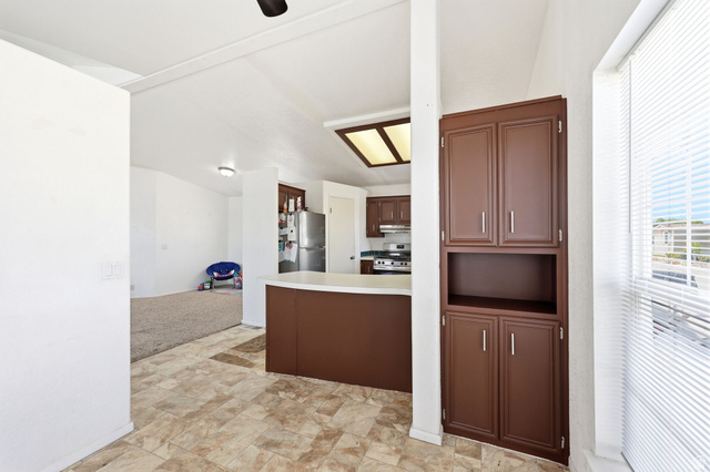 2491 Highway 89, Unit 614 Pleasant View, UT 84404 - Photo 11 of 27 Kitchen with brown cabinetry and light-colored countertops, featuring a built-in pantry cabinet and tiled flooring