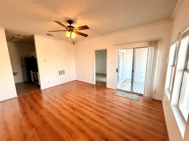 a view of empty room with wooden floor and fan