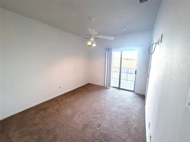 an empty room with windows and ceiling fan