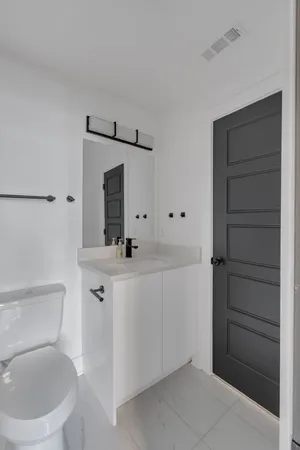 a bathroom with a toilet sink vanity and mirror