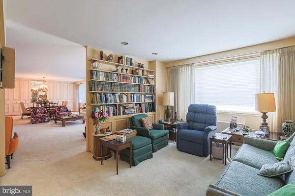 a living room with furniture a bookshelf and a window