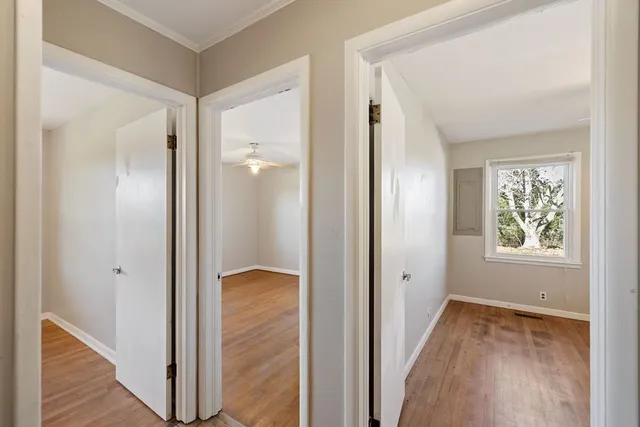 a view of a hallway with wooden floor and a bathroom