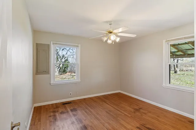 a view of an empty room with a window and wooden floor