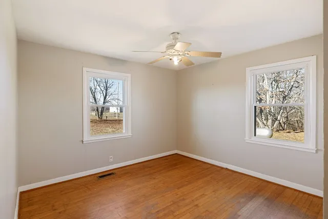 a view of an empty room with a window and wooden floor