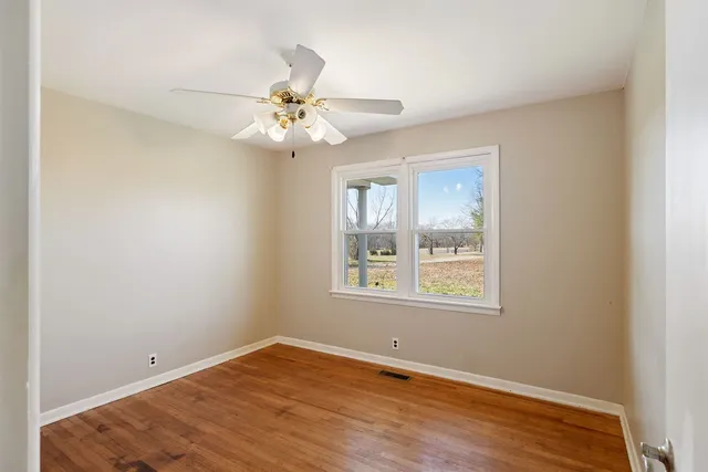 an empty room with a window and a fan