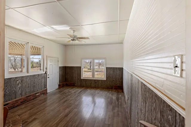 a view of empty room with wooden floor and fan