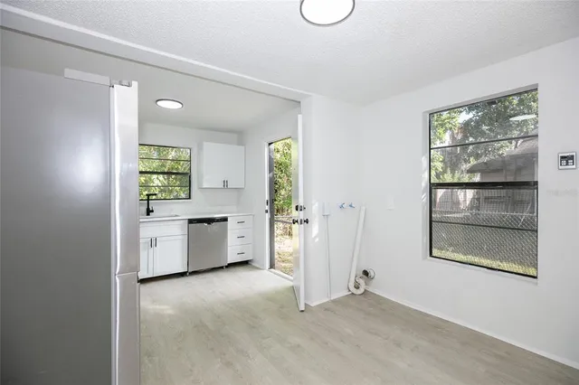 a view of an empty room with a window and kitchen view