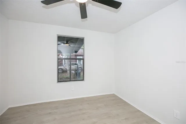 an empty room with wooden floor ceiling fan and windows