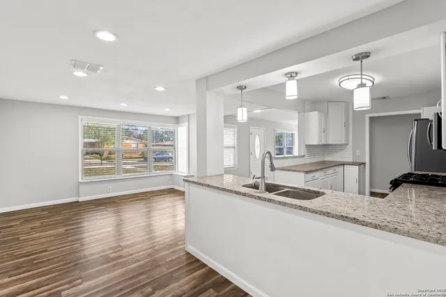 a large kitchen with granite countertop a large counter top a sink and stainless steel appliances