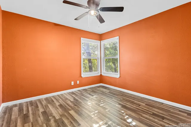 a view of a big room with windows and chandelier fan