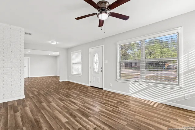 a view of empty room with wooden floor and fan