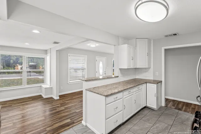 a kitchen with granite countertop white cabinets and a dishwasher