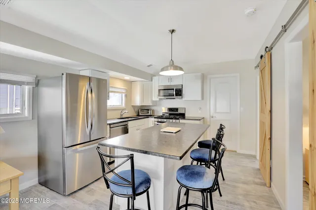 a kitchen with stainless steel appliances kitchen island a table chairs in it and white cabinets