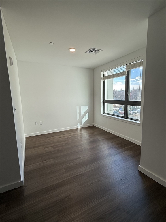 466 River Street, Unit 217 Boston, MA 02126 - Photo 4 of 18 an empty room with wooden floor and windows