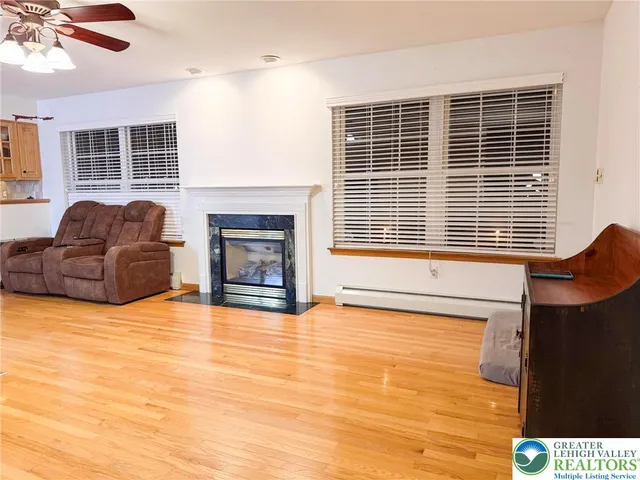 a view of a livingroom with furniture a fireplace a flat screen tv and wooden floor