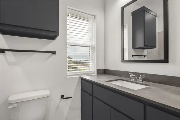 a bathroom with a granite countertop sink toilet and mirror