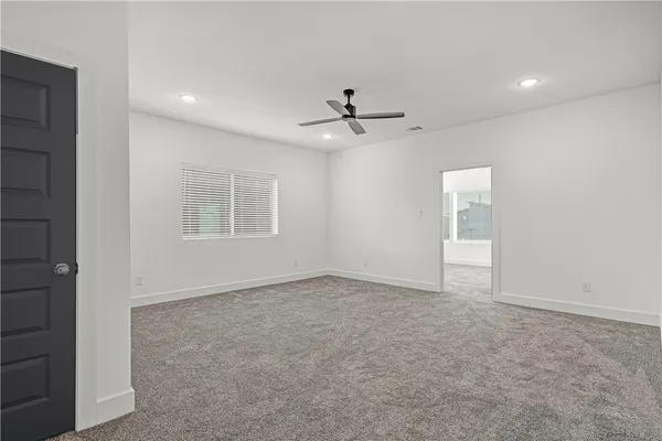 an empty room with windows and ceiling fan
