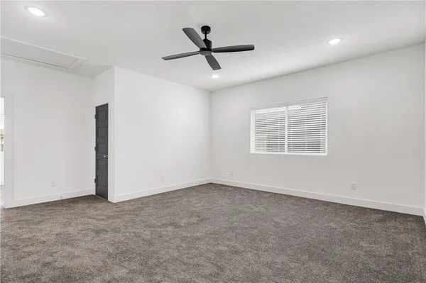 an empty room with ceiling fan and window