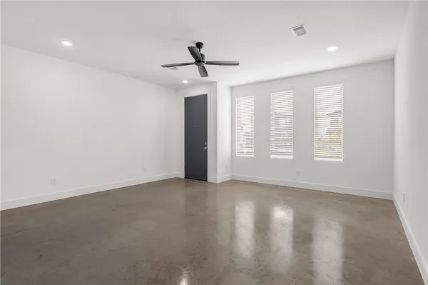 an empty room with windows and ceiling fan