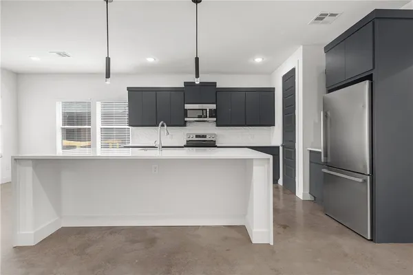 a kitchen with kitchen island a counter top space stainless steel appliances and cabinets