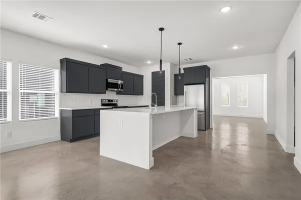 a large kitchen with stainless steel appliances kitchen island granite countertop a stove a sink a refrigerator and a granite counter tops with white cabinets