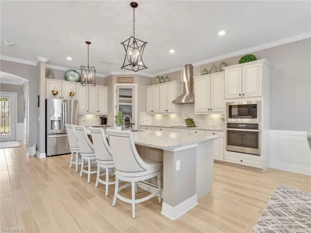 a kitchen with stainless steel appliances kitchen island granite countertop a table chairs and a refrigerator