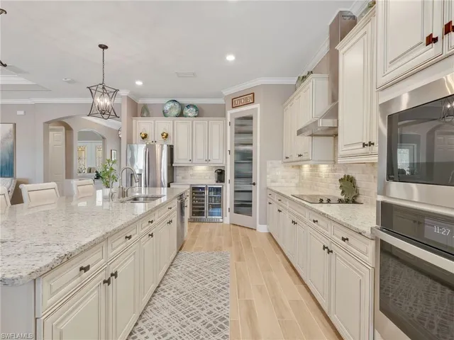 a large kitchen with granite countertop a large white kitchen island white cabinets and stainless steel appliances