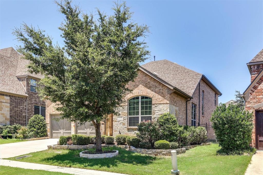 419 Rio Grande Drive Irving, TX 75039 - Photo 3 of 29 Brick and stone exterior featuring an arched window, decorative garage doors, established landscaping, and a stone-edged tree ring