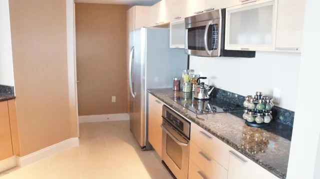 a kitchen with stainless steel appliances kitchen island granite countertop a table chairs in it and a window