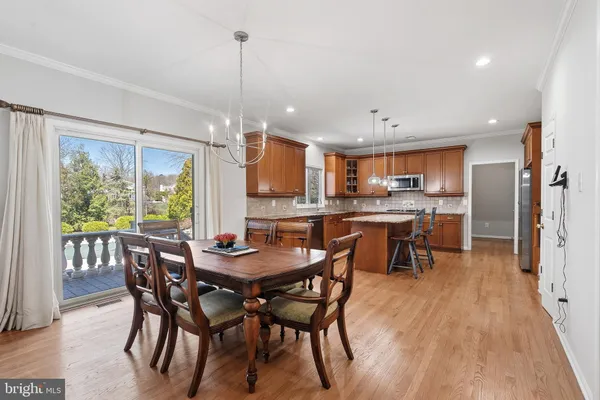 a dining room with stainless steel appliances granite countertop a table chairs and a view of kitchen