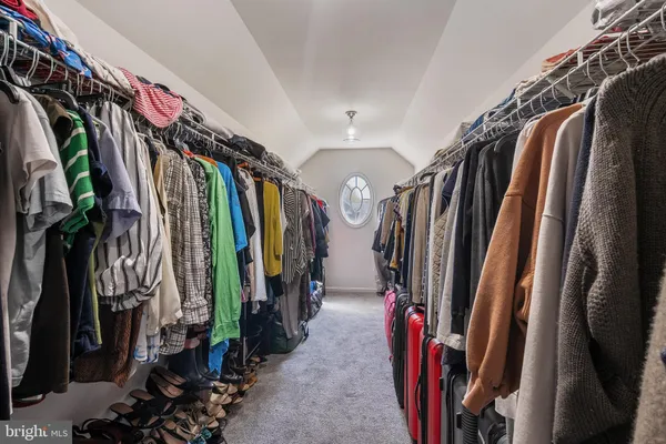 a view of walk in closet with clothes and shoes
