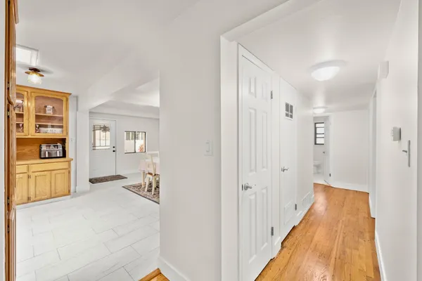 a view of a hallway with wooden floor and a bathroom