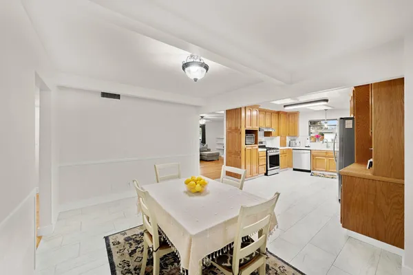 a living room with stainless steel appliances furniture a rug and a view of kitchen