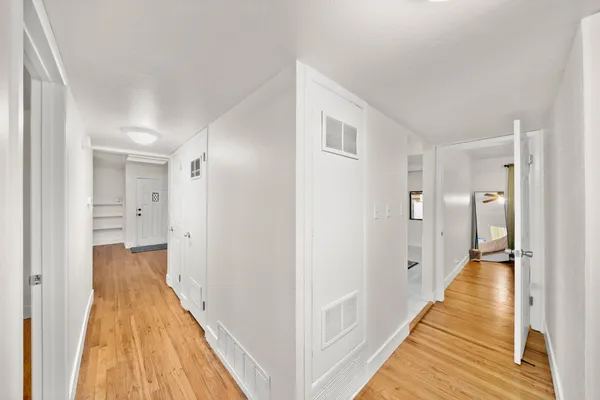 a view of a hallway with wooden floor and a bathroom