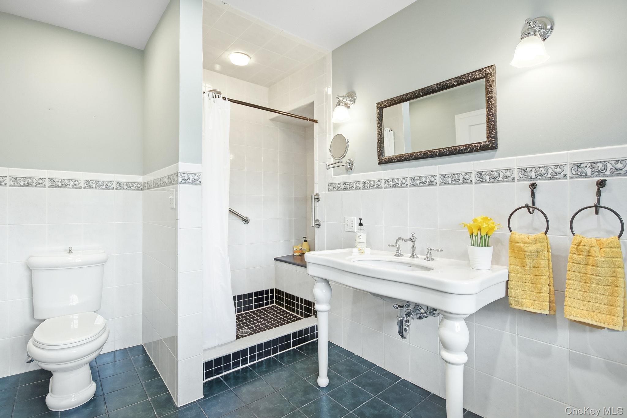 26 Century Ridge Road Purchase, NY 10577 - Photo 18 of 50 Primary en-suite bathroom featuring a walk-in shower with a built-in seat, white subway tile walls with decorative border, and a classic pedestal sink