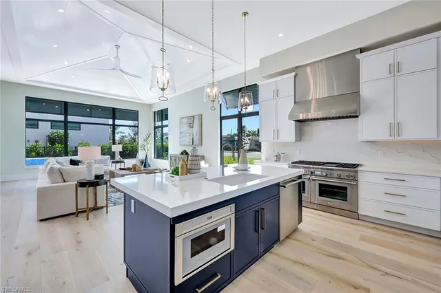 a kitchen with stainless steel appliances granite countertop a stove and a view of living room
