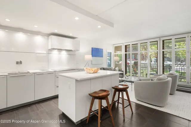 a kitchen with a table chairs wooden floors and white cabinets