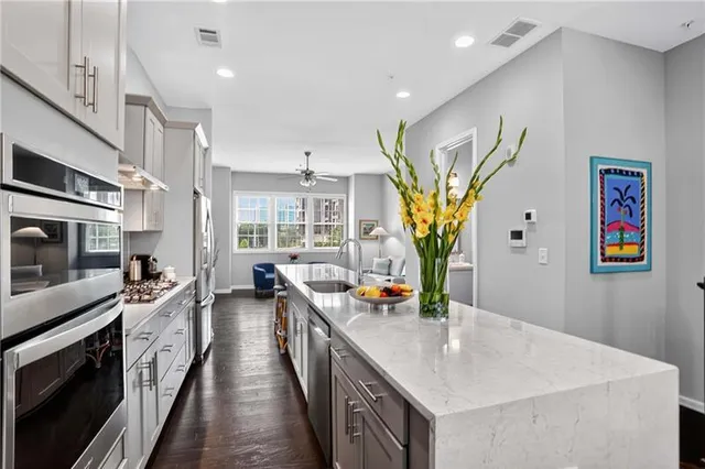 a kitchen with stainless steel appliances granite countertop a sink a stove and a wooden floors