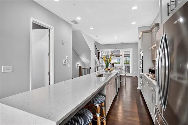 a large kitchen with kitchen island a large window a refrigerator and stainless steel appliances