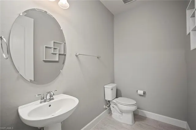 a bathroom with a toilet a sink and mirror
