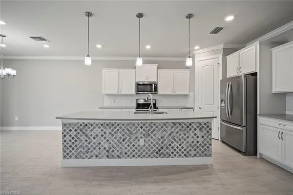 a kitchen with stainless steel appliances granite countertop a refrigerator a sink a stove a microwave and white cabinets