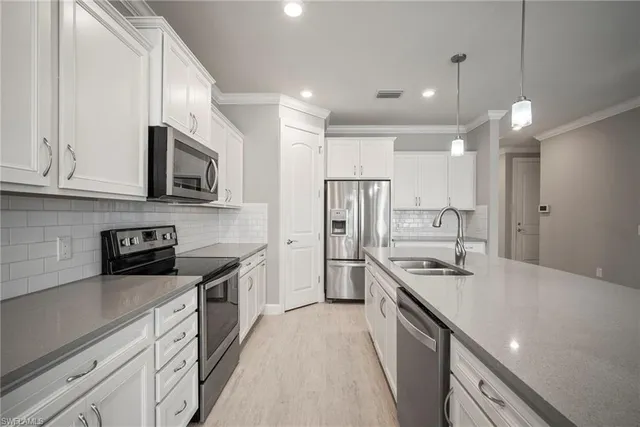 a kitchen with stainless steel appliances a sink stove refrigerator and cabinets