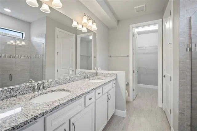 a bathroom with a granite countertop sink a large mirror and a shower