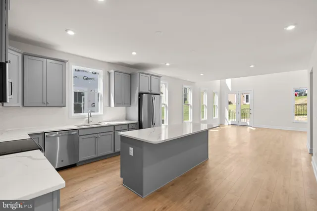 a large kitchen with stainless steel appliances granite countertop a large counter top a sink and a refrigerator