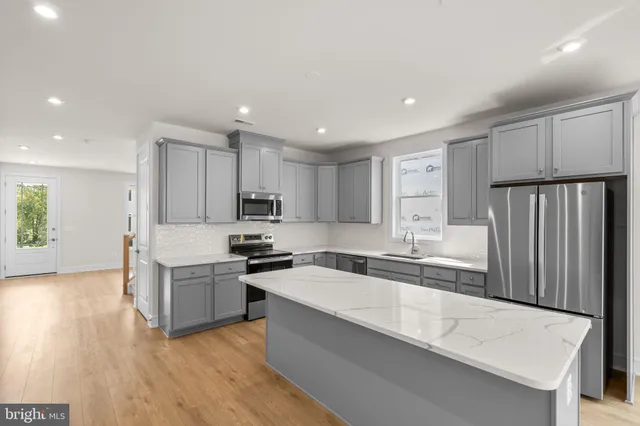 a kitchen with granite countertop a sink a stove a refrigerator cabinets and wooden floor