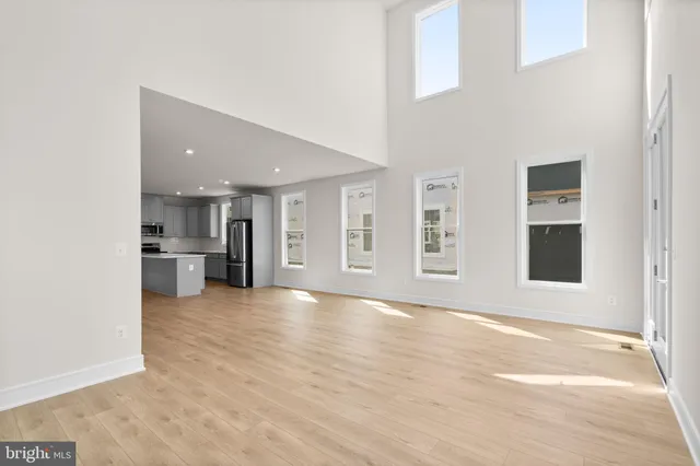 a view of an empty room with kitchen and a window