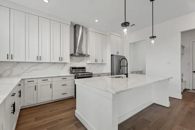 a kitchen with stainless steel appliances granite countertop a sink stove and white cabinets with wooden floor