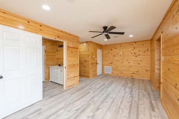 a view of empty room with wooden floor and fan