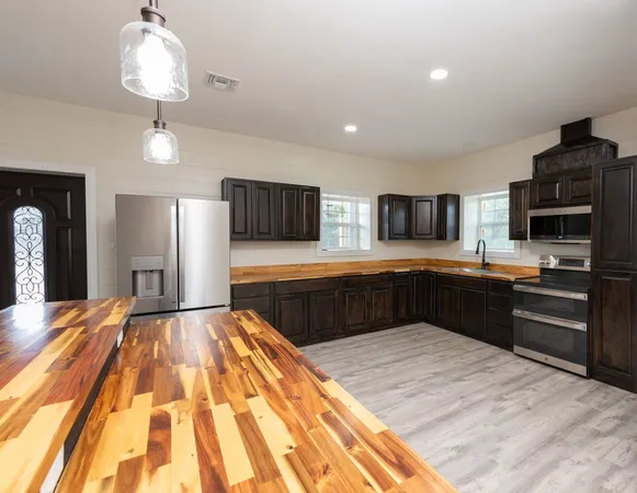 a open kitchen with a refrigerator a stove top oven a counter space and wooden floor